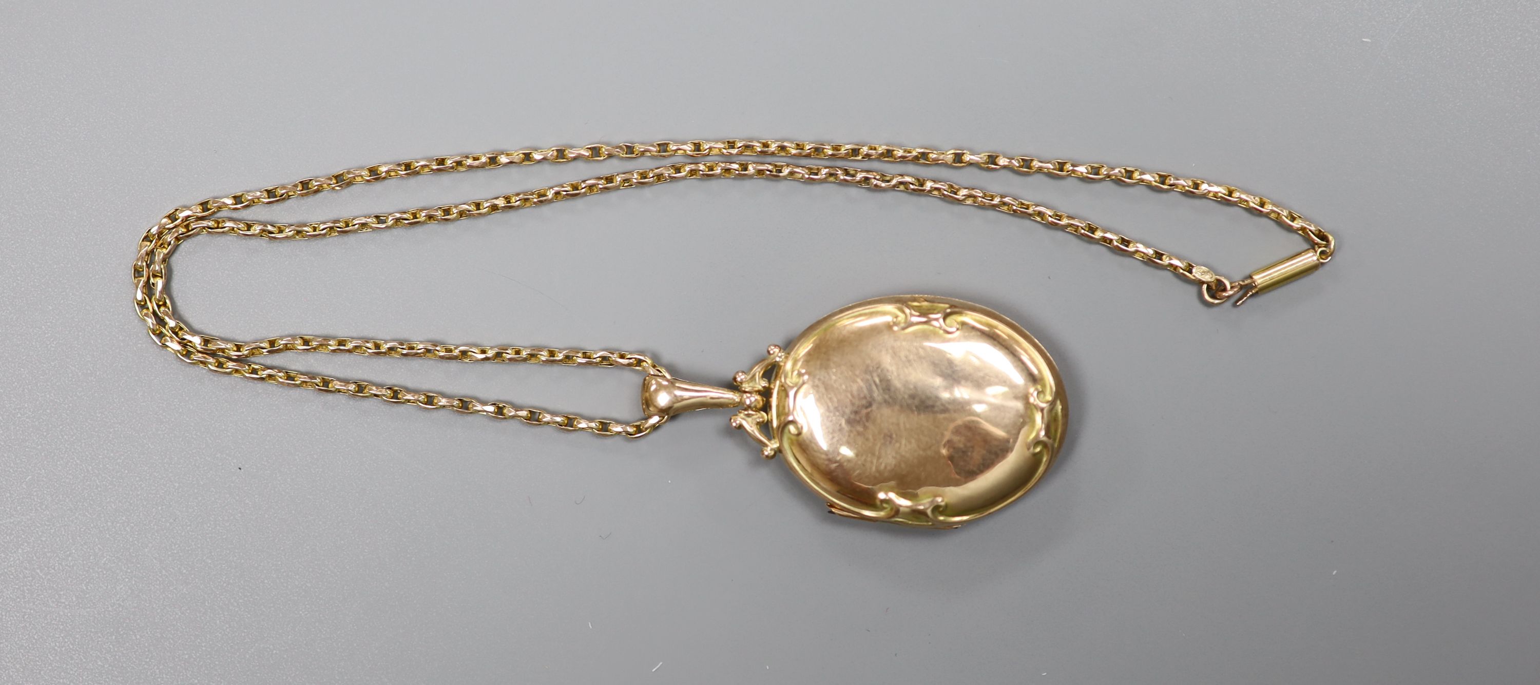 An Edwardian Art Nouveau 9ct gold oval locket, on a 9ct chain